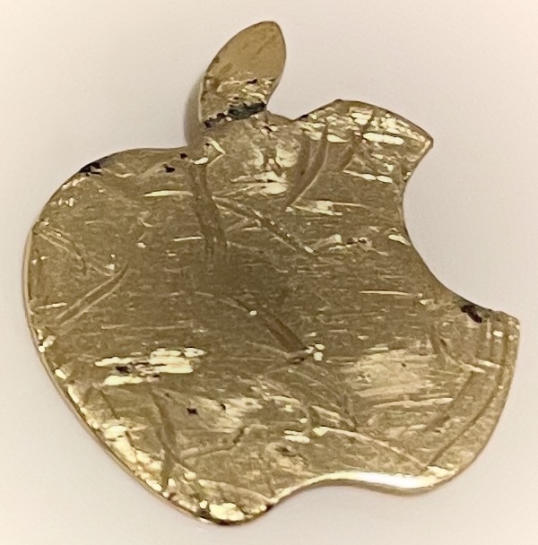 A gold Apple logo, covered in scuffs from being run over, which glint in the light